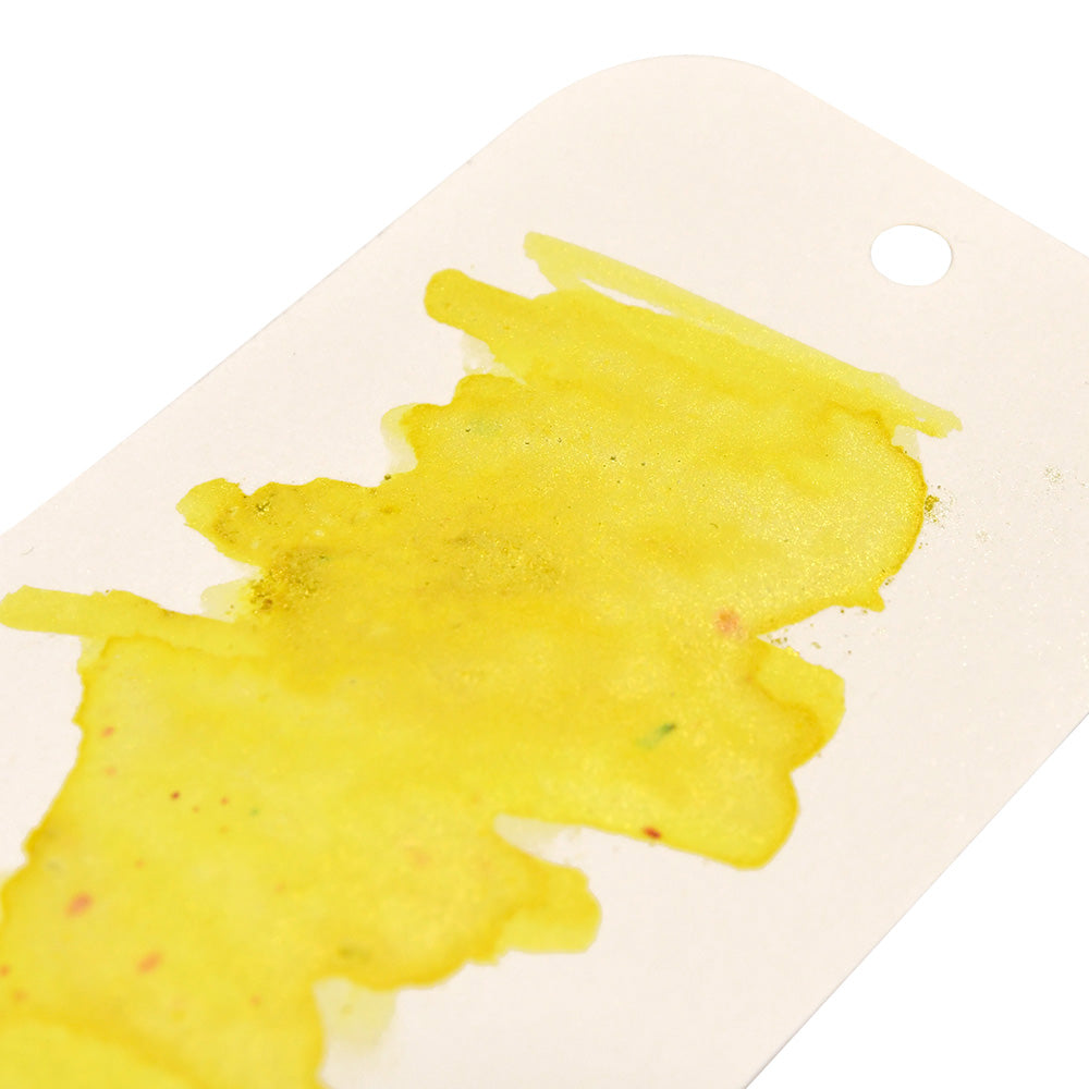 Ein weißer Anhänger von Lindy's Stamp Gang ist mit einem gelben Aquarellfleck aus hochpigmentiertem Pulver versehen und hat ein kleines rundes Loch in der rechten oberen Ecke.