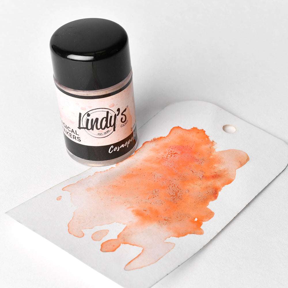 Eine Dose Lindy's Stamp Gang Magical Shakers und ein weißer Anhänger zeigen ein orangefarbenes Aquarellmuster, das mit hochpigmentiertem Pulver für eine einzigartige Farbgebung hergestellt wurde.