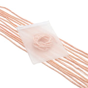 Mehrere lange, blassrosa Garnstränge und ein rundes Stück Garn liegen auf einem durchscheinenden weißen Beutel von ☆, der an handgenähte Geschenkverpackungen erinnert und zart mit einer Seidenschnur verziert ist.
