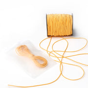 Eine Spule gelbes Alexandra Renke Elastikband mit etwas abgewickeltem, daneben ein aufgewickeltes Stück in einem Klarsichtbeutel - ideal für jedes Bastelprojekt.