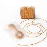 Eine Spule hellbrauner Kordel und ein aufgerollter Gummiband von Alexandra Renke in einem gefrosteten Plastikbeutel, ideal für Bastelprojekte, auf weißem Hintergrund.