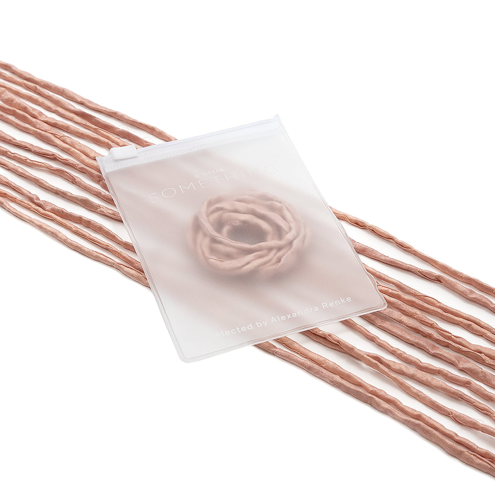 Ein durchscheinender ☆ Beutel mit zartem Blumenmuster ruht auf einer gedrehten rosa Seidenschnur und eignet sich somit perfekt für handgenähte Geschenkverpackungen.