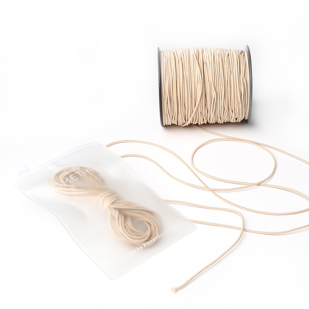Beiges Elastikband auf Spule, inkl.. Schnur und Gummiband, in transparenter Tasche - ideal für Bastelprojekte. Marke: Alexandra Renke.