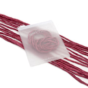 Ein durchscheinender Beutel von ☆ mit einem Rosenmotiv auf der Innenseite ruht auf strukturierten, weinroten Stoffstreifen, ist sorgfältig von Hand genäht und mit einer eleganten Seidenschnur verziert – perfekt für exquisite Geschenkverpackungen.