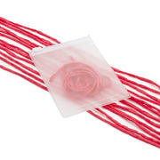 Ein mattierter Beutel von ☆, in dem eine rosa Rose zu sehen ist, ruht auf mehreren Strängen rosa Garn und zarter Seidenschnur – ein bezauberndes Arrangement, das sich perfekt für liebevolle Geschenkverpackungen eignet.