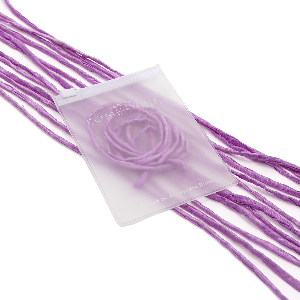 Ein durchscheinender Beutel von ☆ mit handgenähten Kanten und einer violetten Seidenschnur im Inneren, präsentiert auf mehreren Strängen loser violetter Schnüre – perfekt für die Gestaltung einzigartiger Geschenkverpackungen.