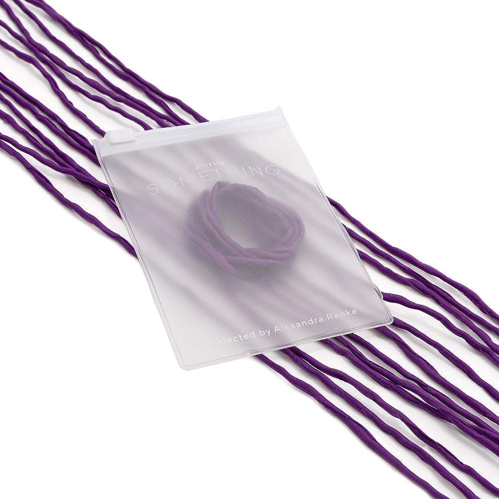 Ein durchscheinender Beutel mit einer handgenähten violetten Seidenschnur von ☆, akzentuiert durch weitere violette Bänder vor weißem Hintergrund – perfekt für elegante Geschenkverpackungen.