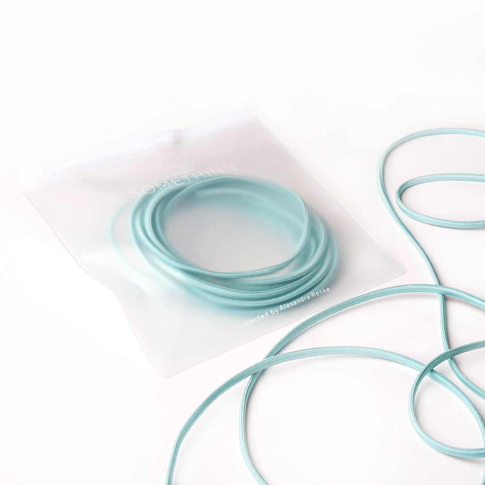 Ein tealfarbenes, gewickeltes Elastikband von Alexandra Renke in einer durchsichtigen Reißverschlusstasche, mit zusätzlicher Kordel auf weißem Hintergrund - ideal für Ihr nächstes Bastelprojekt.