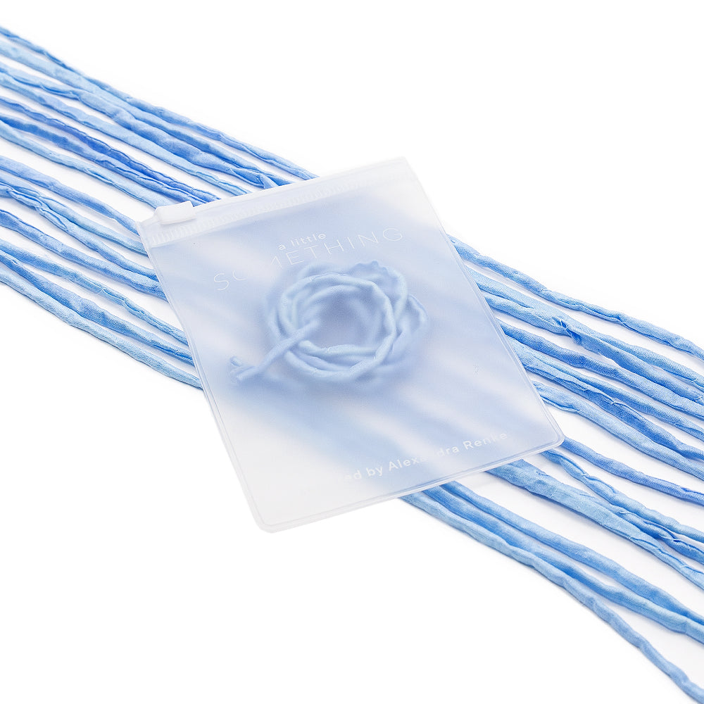 Ein durchscheinender Beutel von ☆, handgenäht für eine einzigartige Note, aus dem blaue Garnfäden auf den weißen Hintergrund herausragen – eine bezaubernde Wahl für Geschenkverpackungen.