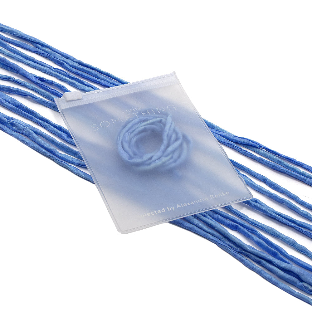 Ein mattierter Beutel mit der Aufschrift ☆, in dem sich elegante blaue Seidenschnur-Kordeln befinden, die sich auf weißem Hintergrund nach außen erstrecken – perfekt für Geschenkverpackungen und mit handgenähter Verarbeitung.