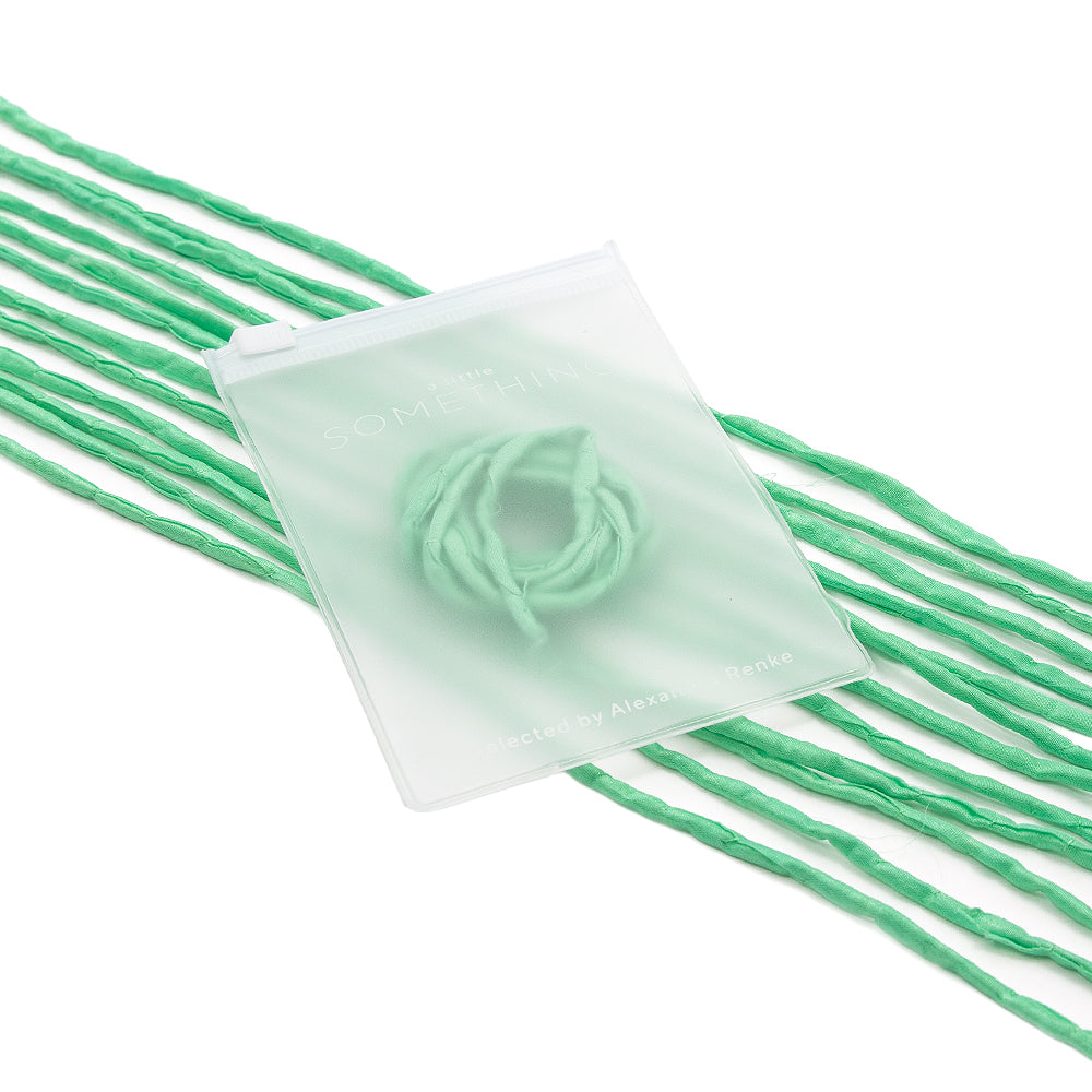 Durchsichtige Karte von ☆ mit grünen Seidenschnur-Schlaufen – sorgfältig von Hand genäht –, die zwischen losen grünen Fäden auf weißem Hintergrund angeordnet sind und Geschenkverpackungen eine einzigartige Note verleihen.