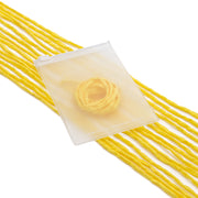 Ein ☆-Buch, dessen Einband mit einer gelben Rose verziert ist, ruht auf mehreren Strängen ungekochter gelber Nudeln; seine Seiten sind zart mit einer feinen Seidenschnur zusammengebunden, was an exquisite Geschenkverpackungen erinnert.