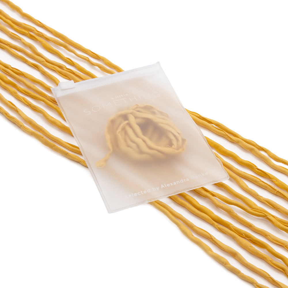 Ein durchscheinender ☆ Beutel präsentiert auf elegante Weise gedrehte gelbe Nudelstränge, wobei der verschwommene Text und die markante Nudelform im Inneren sichtbar sind – perfekt für Geschenkverpackungen. Die handgenähte Verarbeitung und die edle Seidenschnur verleihen dieser reizvollen Präsentation eine einzigartige, handwerkliche Note.