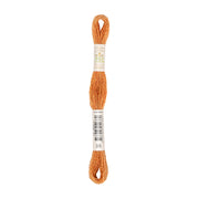 Ein Strang orangefarbenes Stickgarn mit Etiketten, die um die Mitte und das untere Ende gewickelt sind – dieses Stickgarn wird aus natürlich gefärbtem Garn hergestellt und sorgt für lebendige, umweltfreundliche Stickereien.