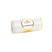 Eine Spule DMC Diamant Garn Metallic-Stickgarn in Silber mit einem goldenen und weißen Etikett, ideal, um Ihren Stickprojekten einen schimmernden Metalleffekt zu verleihen.