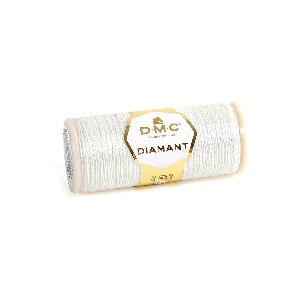 Eine Spule DMC Diamant Garn Metallic-Stickgarn in Silber mit einem goldenen und weißen Etikett, ideal, um Ihren Stickprojekten einen schimmernden Metalleffekt zu verleihen.