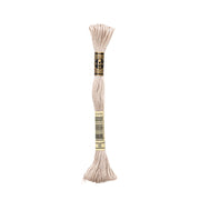 Ein Knäuel beigefarbenes DMC Stickgarn aus 100% Baumwolle mit einem schwarz-goldenen Etikett, isoliert auf weißem Hintergrund.