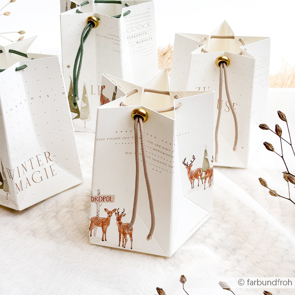 Vier weiße, sternförmige Geschenktüten mit Hirschmotiven und einer dekorativen Nylon-Flechtkordel.