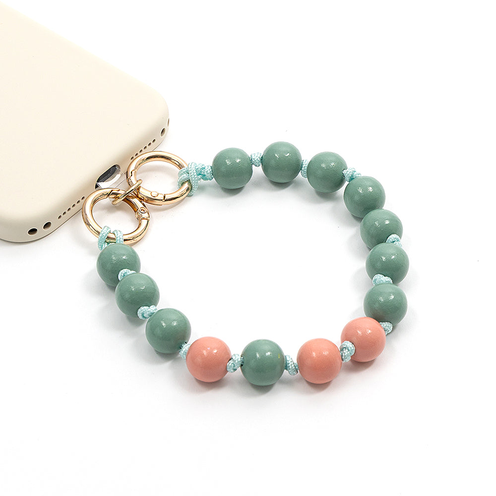 Ein ☆ Handy-Accessoire mit einem Perlenband aus grünen und rosa runden Perlen an einer blauen Makramee-Flechtkordel.