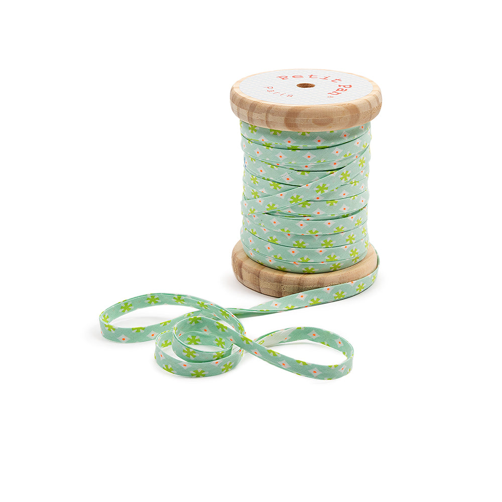 Eine Holzspule mit grünem Schrägband, verziert mit kleinen weißen und gelben Blümchen – ideal zum Nähen und zum Versäubern von Stoffkanten mit einem charmanten Touch.