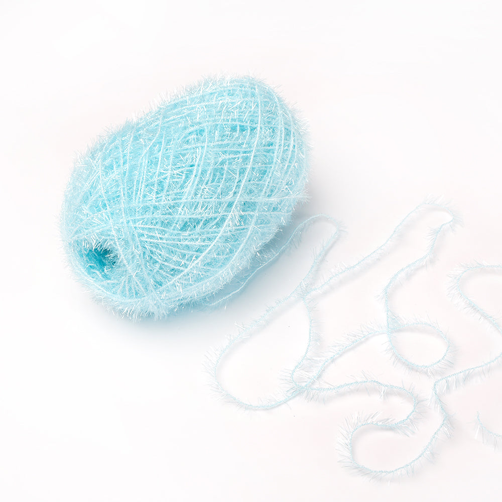 Ein Knäuel hellblaues, flauschiges Rico Design Creative Bubble-Garn mit einigen losen Fäden daneben auf weißem Grund - perfekt zum Häkeln von Geschirrtüchern.