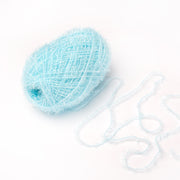 Ein Knäuel hellblaues, flauschiges Rico Design Creative Bubble-Garn mit einigen losen Fäden daneben auf weißem Grund - perfekt zum Häkeln von Geschirrtüchern.