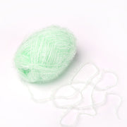 Ein Knäuel aus hellgrünem, krausem Rico Design Garn - ideal als robustes Garn für Häkeln Spüllappen - liegt mit einem losen Strang auf weißem Grund.