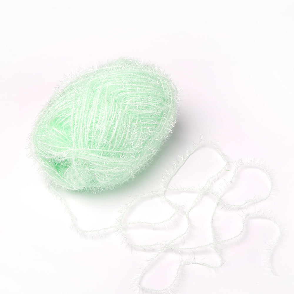 Ein Knäuel aus hellgrünem, krausem Rico Design Garn - ideal als robustes Garn für Häkeln Spüllappen - liegt mit einem losen Strang auf weißem Grund.