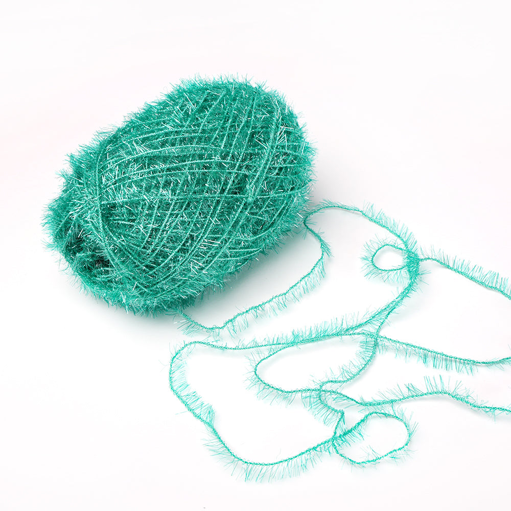 Ein blaugrünes Knäuel des flauschigen Rico Design Creative Bubble Garns mit einem losen Strang auf weißem Grund - ideal für das Häkeln von Geschirrtüchern aufgrund seiner haltbaren Textur.