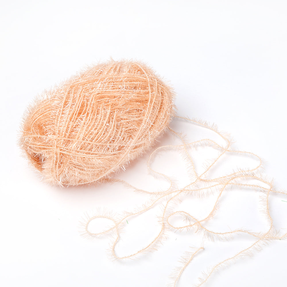 Ein pfirsichfarbener Fuzzy-Garnball von Rico Design, ideal für Häkel-Spüllappen, mit einem losen Strang auf weißem Grund - dieses robuste Garn bringt Charme und Zweckmäßigkeit in Ihre kreativen Bubble Garn Projekte.