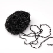 Ein Knäuel aus schwarzem, glitzerndem Rico Design Creative Bubble Garn mit einem losen Strang liegt auf weißem Grund - ideal zum Häkeln von Geschirrtüchern und anderen kreativen Projekten.