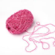 Eine Kugel aus glitzerndem rosa Rico Design Creative Bubble Garn mit einem lockeren, flockigen Strang erstreckt sich auf weißem Hintergrund - ideal für Spüllappen häkeln aufgrund seiner robusten Garnstruktur.