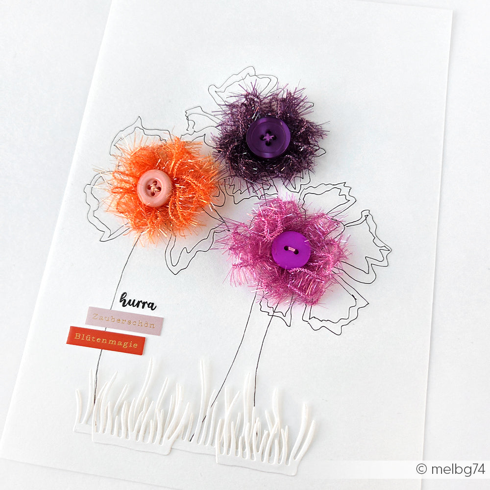 Handgefertigte Karte mit drei Blumen, die mit Rico Design Creative Bubble Garn und Knöpfen auf gezeichneten Stängeln hergestellt wurden, veredelt mit deutschen Textstickern.