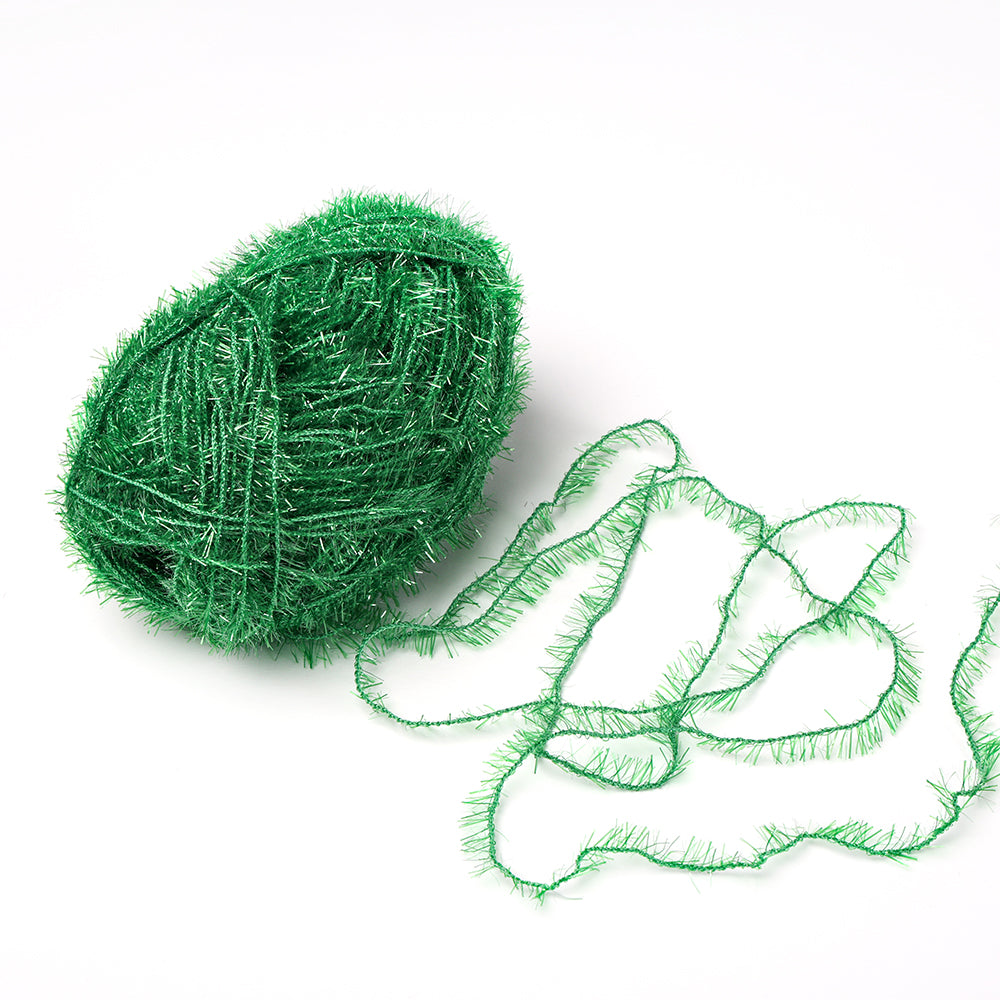 Ein Knäuel des glitzernden grünen Rico Design Creative Bubble Garns mit einem losen Strang auf weißem Grund - ideal zum Häkeln von Geschirrtüchern.