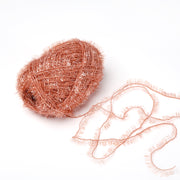 Eine Kugel aus glänzendem, strukturiertem kupferfarbenem Rico Design Creative Bubble Garn mit einem losen Strang sitzt auf einem weißen Hintergrund - perfekt für Spüllappen häkeln oder jedes Projekt, das robustes Garn benötigt.