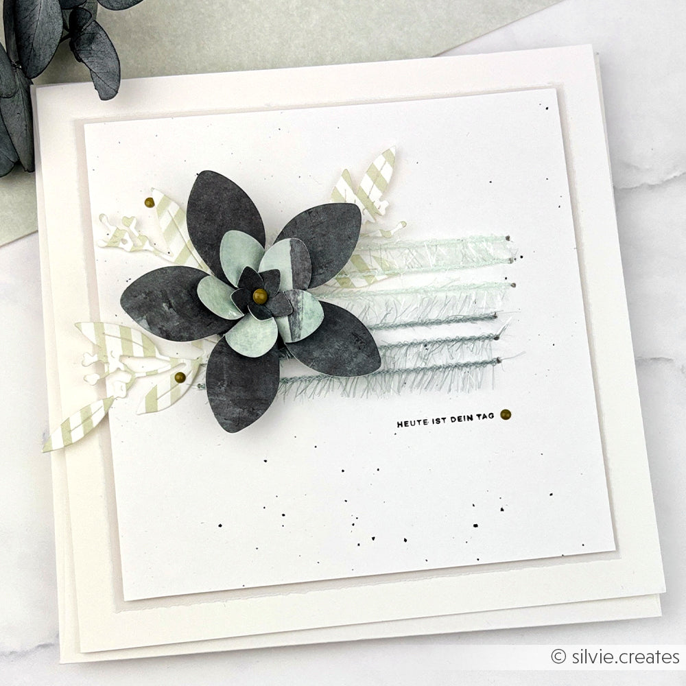 Handgefertigte Rico Design-Karte mit einer geschichteten Papierblume, strukturierten Linien und dem deutschen Text "HEUTE IST DEIN TAG" - veredelt mit robuster Schnur für zusätzlichen Charme.
