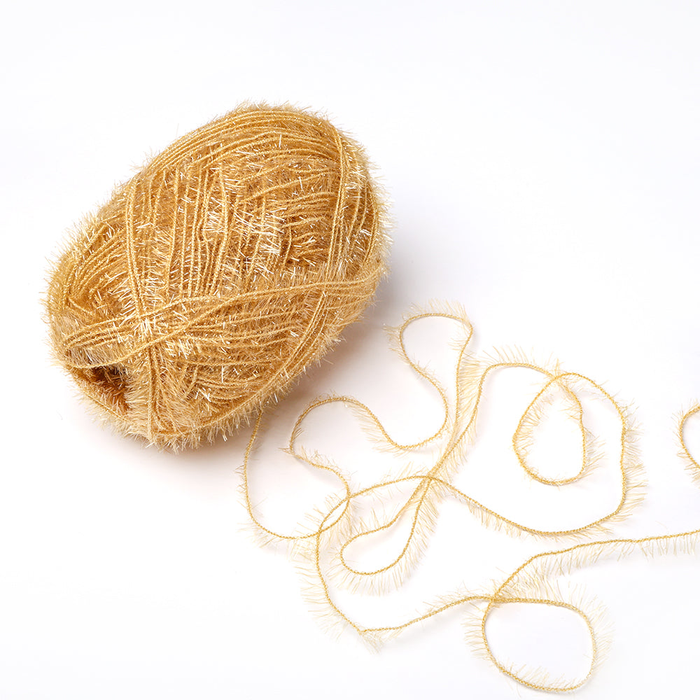 Ein Knäuel goldglänzendes Rico Design Creative Bubble-Garn mit flauschiger Textur und losem Strang liegt auf einem weißen Hintergrund.