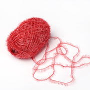 Ein Knäuel des roten, glitzernden Rico Design Creative Bubble Garns mit losem Faden und Schlingen liegt auf weißem Grund - ideal zum Häkeln von Spüllappen.