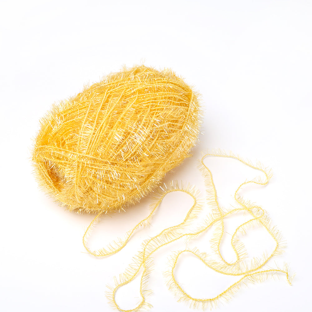 Ein Knäuel des gelben, glitzernden Rico Design Garns, perfekt für Spüllappen häkeln, mit einem losen Strang auf weißem Hintergrund.