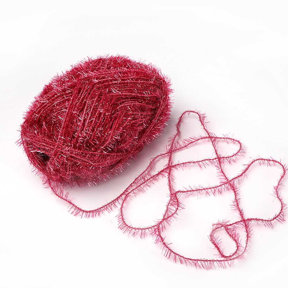 Ein glitzernder roter Rico Design Creative Bubble-Garnball mit einem lockeren, gekräuselten Strang auf weißem Hintergrund - perfekt zum Häkeln von Geschirrtüchern oder anderen kreativen Projekten.