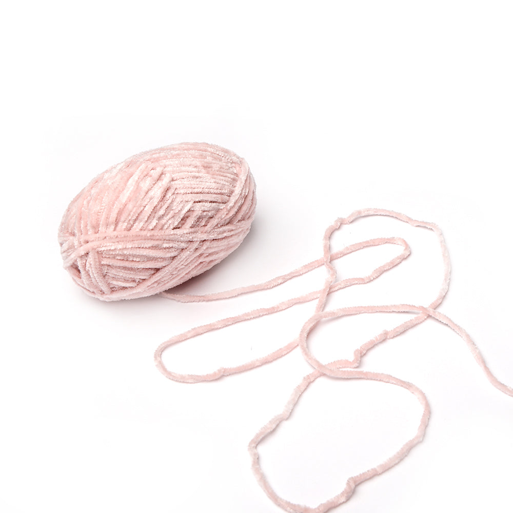 Ein Knäuel aus hellrosa superflauschigem Garn von Rico Design mit einem losen Strang auf weißem Hintergrund - perfekt für Amigurumi-Häkelprojekte.