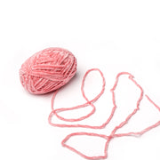 Ein Knäuel des rosafarbenen Chenille-Garns von Rico Design mit einem losen Faden auf weißem Grund - ideal zum Häkeln von ultraweichen Schals.
