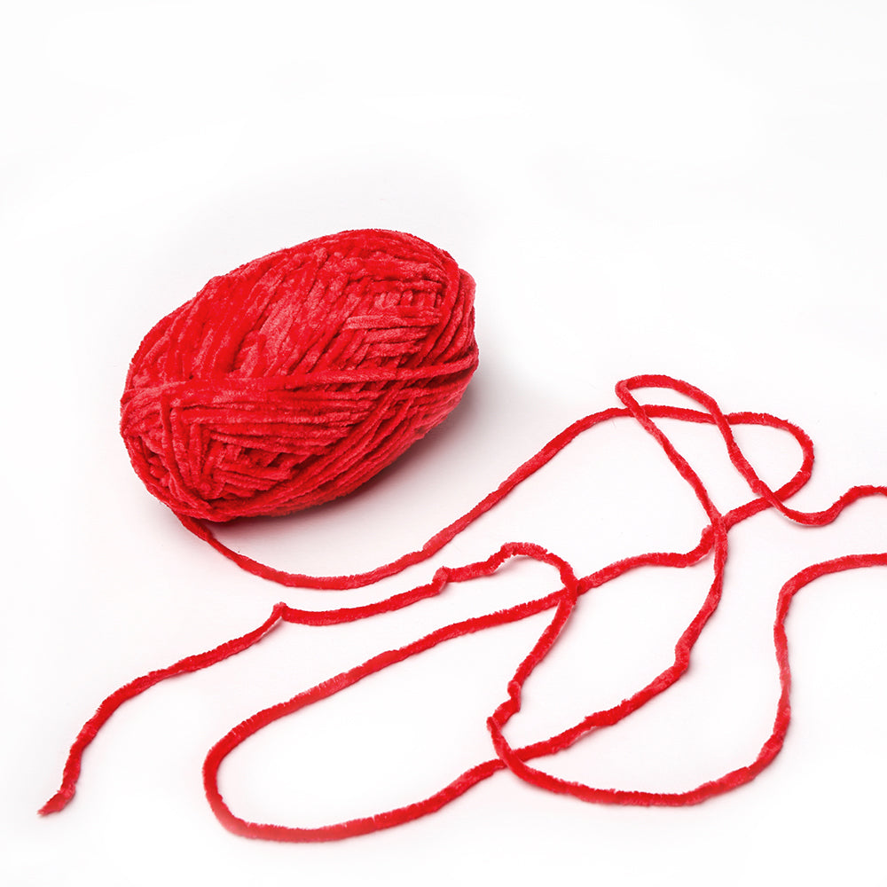 Ein rotes Garnknäuel von Rico Design mit einem losen Strang auf weißem Grund, mit superfluffiger Chenille-Textur - perfekt zum Häkeln von Babyartikeln.