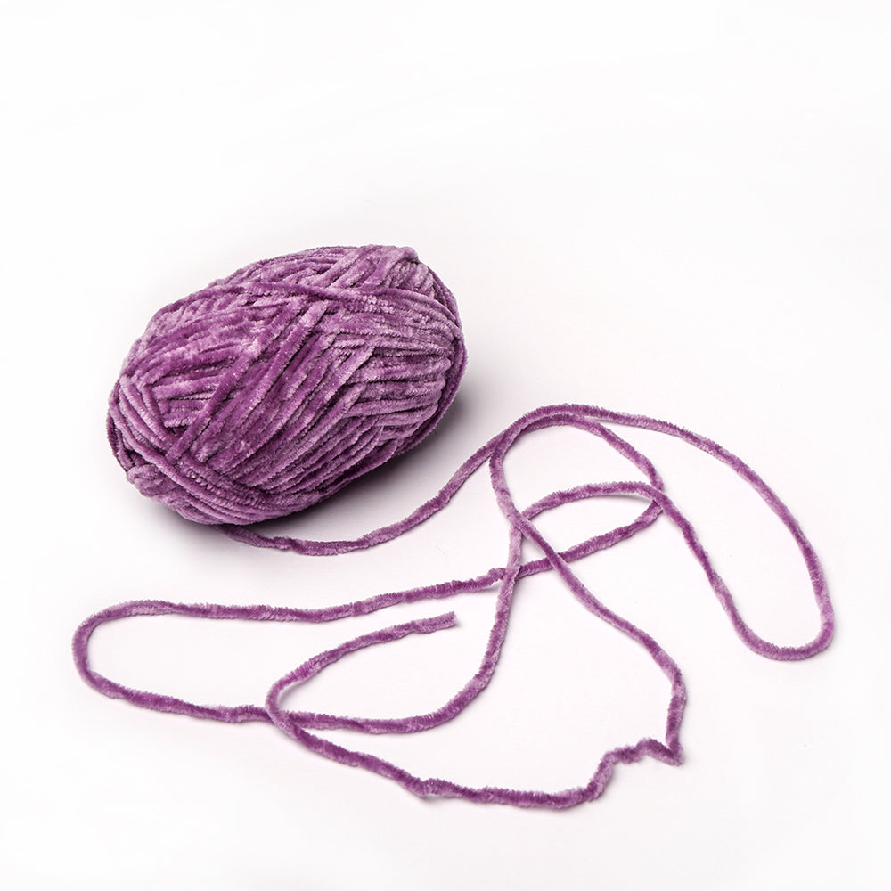Eine Kugel aus lilafarbenem kuschelweichem Garn von Rico Design mit einem losen Strang auf weißem Hintergrund.