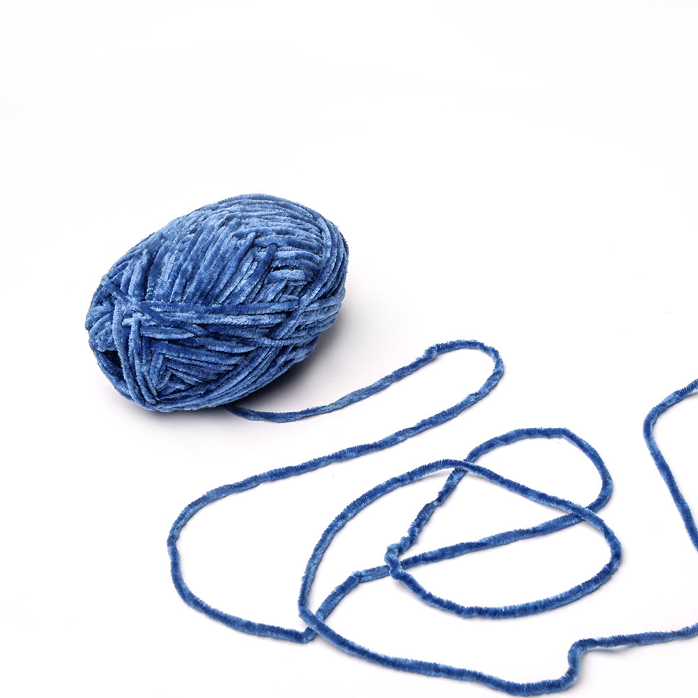 Ein Knäuel blaues, superflauschiges Garn von Rico Design mit einem losen Strang auf weißem Grund - durch seine weiche Chenille-Struktur ideal für Häkelprojekte.