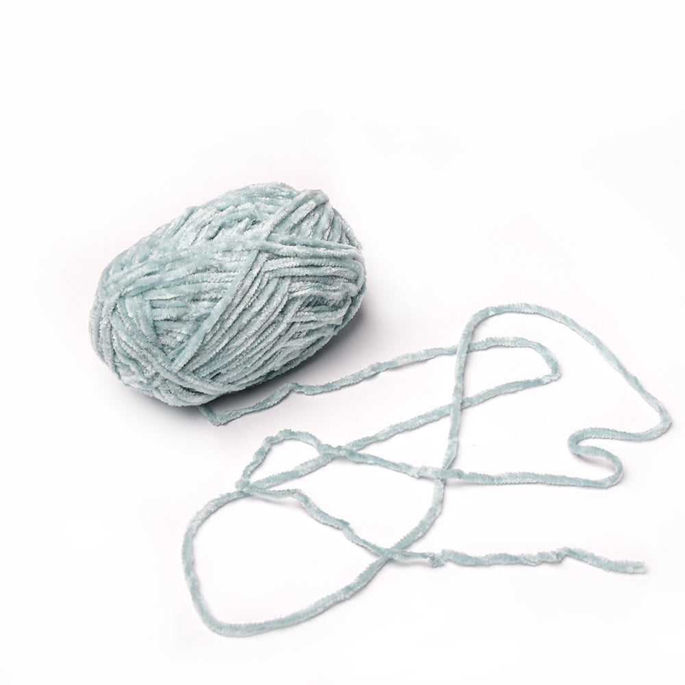 Ein hellblauer Ball aus superflauschigem Garn von Rico Design mit Chenille-Struktur und einem losen Strang, perfekt zum Häkeln, auf weißem Hintergrund.
