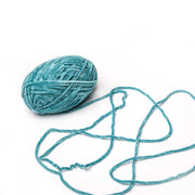 Ein Knäuel tealfarbenes Rico Design Chenille-Garn mit einem losen Strang, der sich auf weißem Grund auflöst - ideal zum Häkeln von weichen Kuscheltieren.