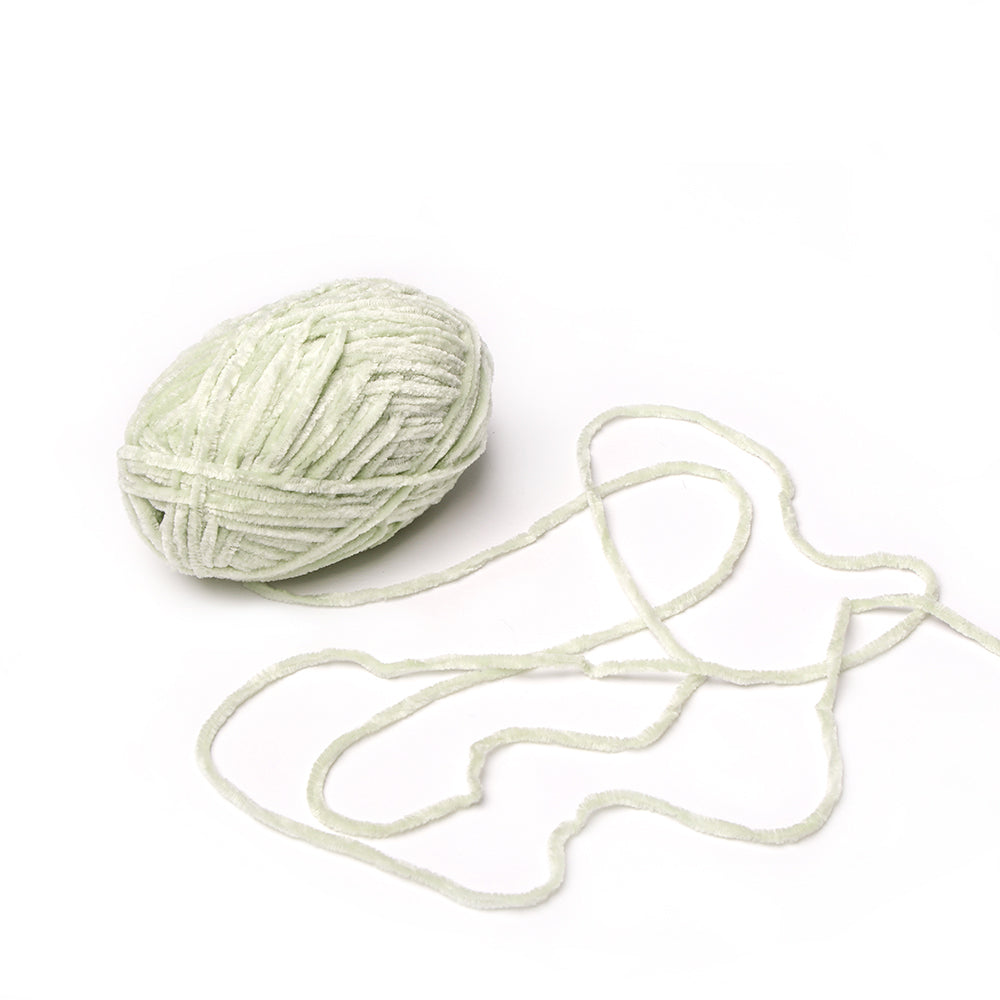 Ein hellgrünes Knäuel von Rico Design Chenille Garn mit einem losen Strang auf weißem Grund, perfekt für Häkeln Projekte und gefärbt mit speichelechter Farbe.
