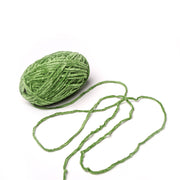 Ein Knäuel grünes Kuschelgarn von Rico Design mit einer losen Strähne auf weißem Hintergrund.