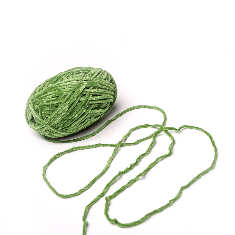 Ein Knäuel grünes Kuschelgarn von Rico Design mit einer losen Strähne auf weißem Hintergrund.